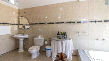 Um banheiro com pia de pedestal, vaso sanitário, bidê e banheira.