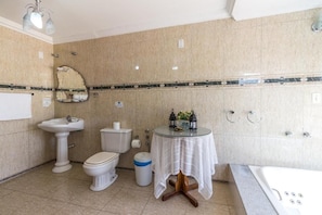 A bathroom with a pedestal sink, toilet, bidet, and bathtub.