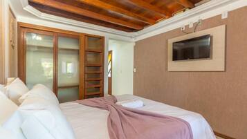 Quarto com cama, televisão presa na parede e guarda-roupa com porta de correr.