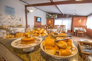 A buffet area with various baked goods and a television in the background.