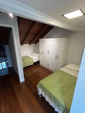 Une chambre avec deux lits, une armoire et un plafond en pente.