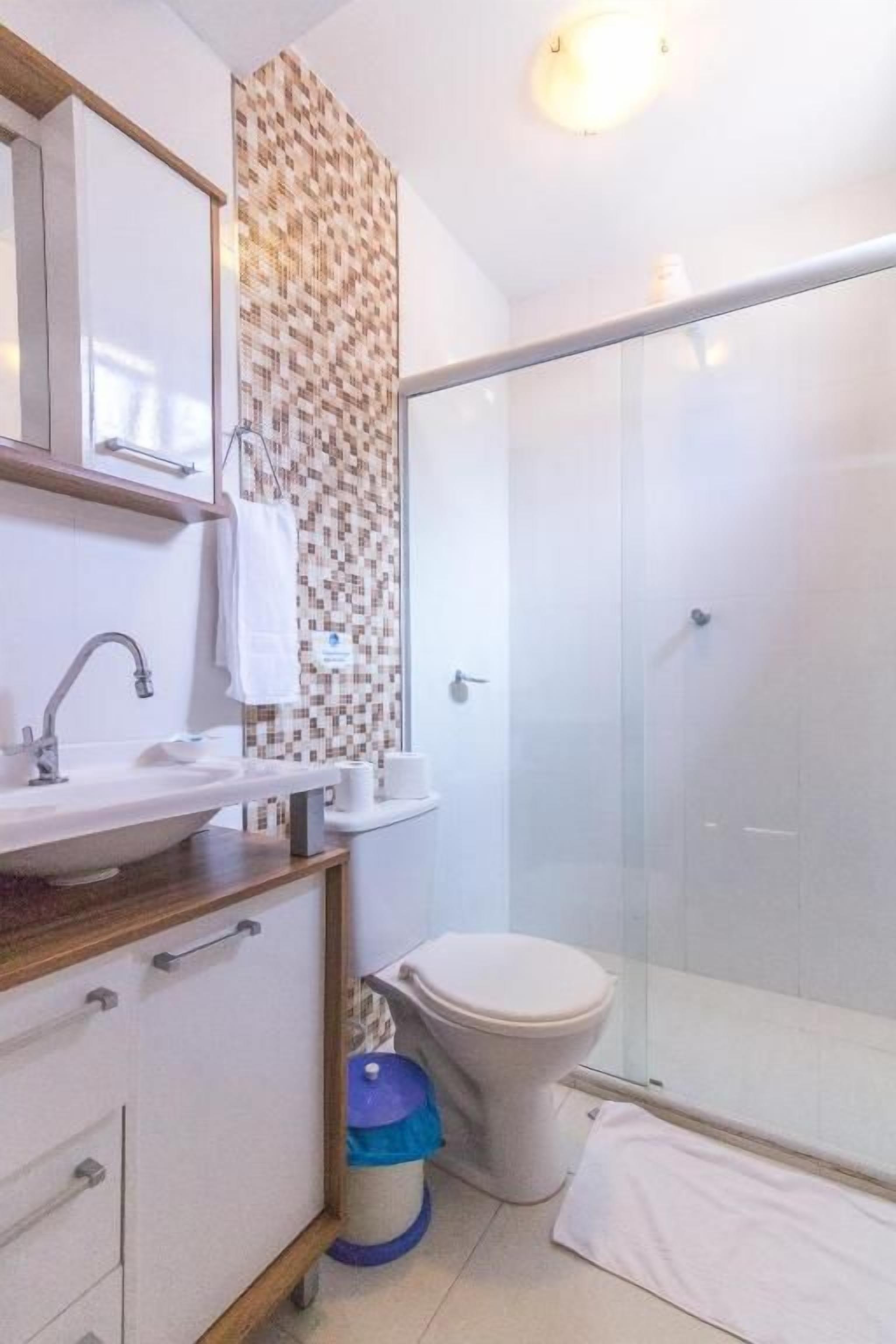 A bathroom with a shower, toilet, sink, and a patterned wall.