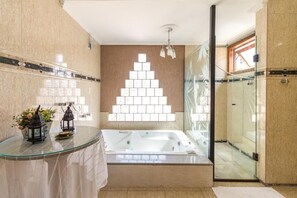Un baño moderno con ducha envuelta en vidrio, una bañera independiente y un panel decorativo en la pared.