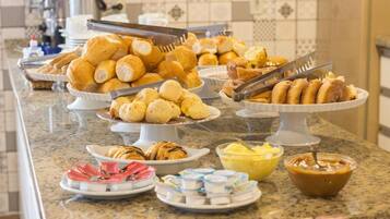 A buffet with various food items including pastries, bread, and condiments.