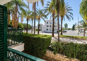 A residential area with a street view, palm trees, and a white building with balconies. - Casa das Chaminés – In Conceicao de Tavira (Tavira)