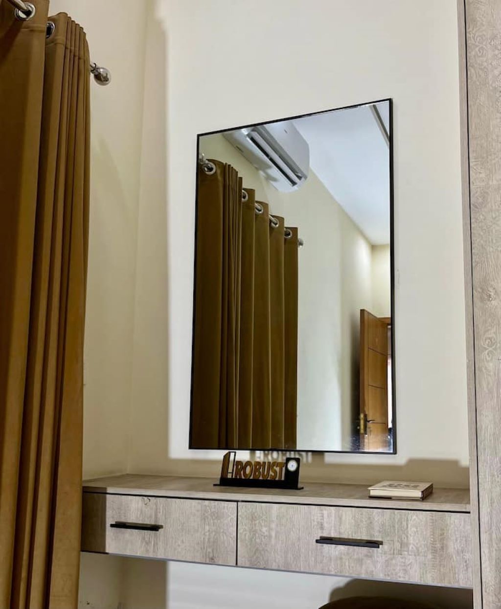 A bathroom with a mirror, a towel rack, and a cabinet with a 'ROBUST' sign.