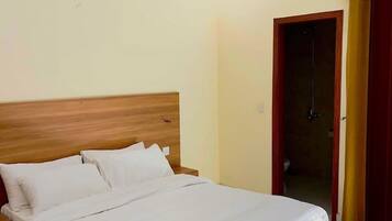 Quarto com cama de madeira, roupa de cama branca, ventilador de teto e ar condicionado.