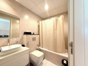 A modern bathroom with a sink, toilet, and bathtub. - Modern Studio in Dubai - Pool, Gym & Parking (Dubai)