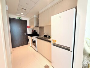 A modern kitchen with a built-in oven, microwave, and refrigerator. - Modern Studio in Dubai - Pool, Gym & Parking (Dubai)