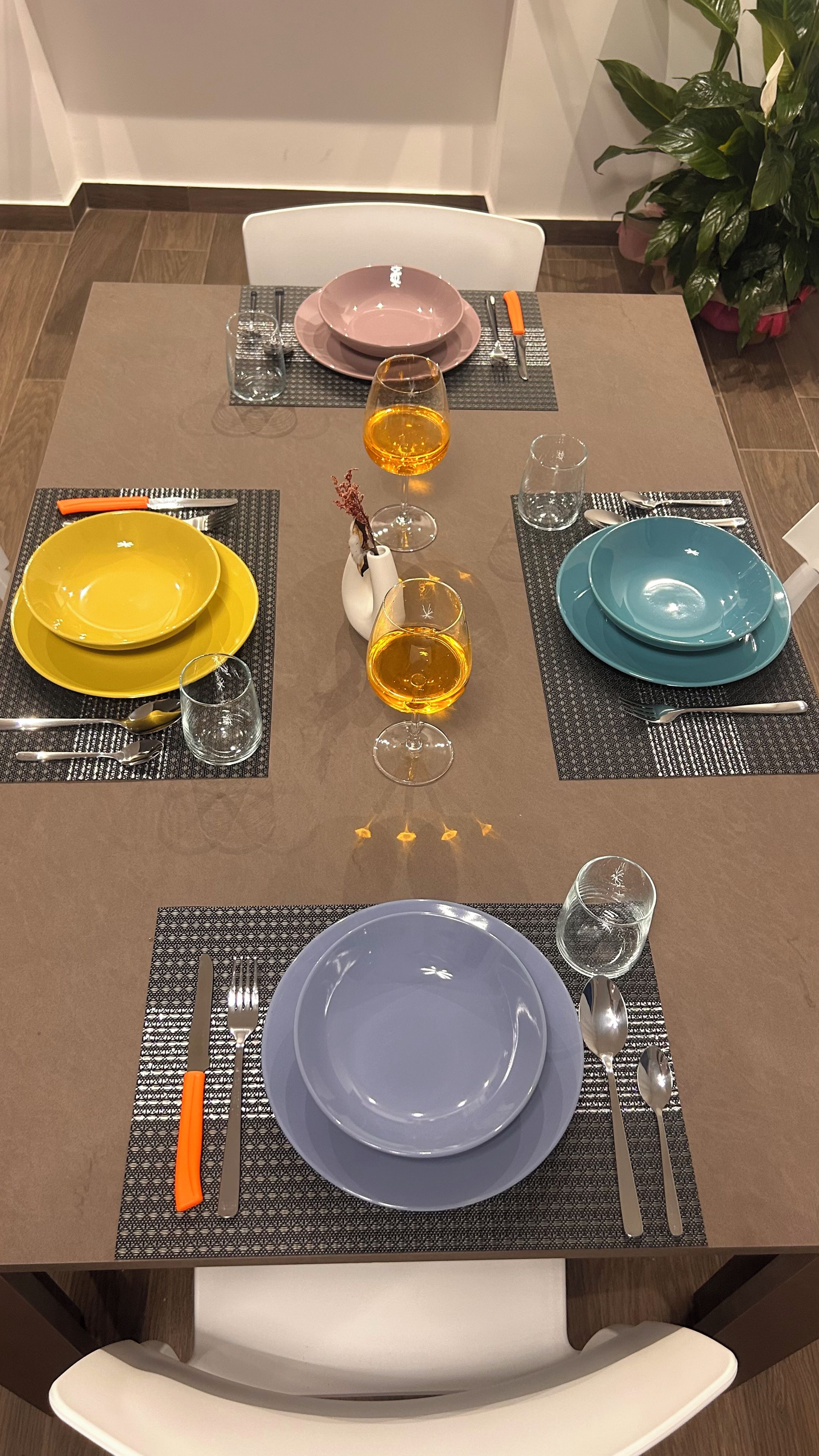 Una mesa de comedor dispuesta con platos, vasos y cubiertos.