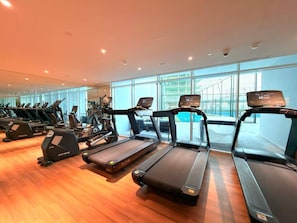 Ein Fitnessstudio mit mehreren Laufbändern, Ergometer und einem großen Fenster mit Blick nach außen.
