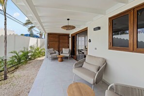 Ein moderner Außenbereich mit überdachter Terrasse, Sitzgelegenheiten und Blick auf die Straße.