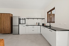 Eine moderne Küche mit weißen Schränken, einem Edelstahlkühlschrank und einer schwarzen Arbeitsplatte.
