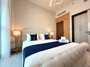 Una camera d'albergo con un letto grande, due lampade ai lati del letto, un armadio e una porta con un motivo geometrico.