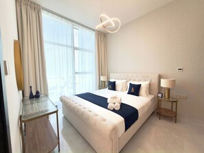 A hotel room with a large bed, a desk, a lamp, and a modern light fixture. - Stylish 1BR Apartment - Skyz by Danube - Arjan (Dubai)