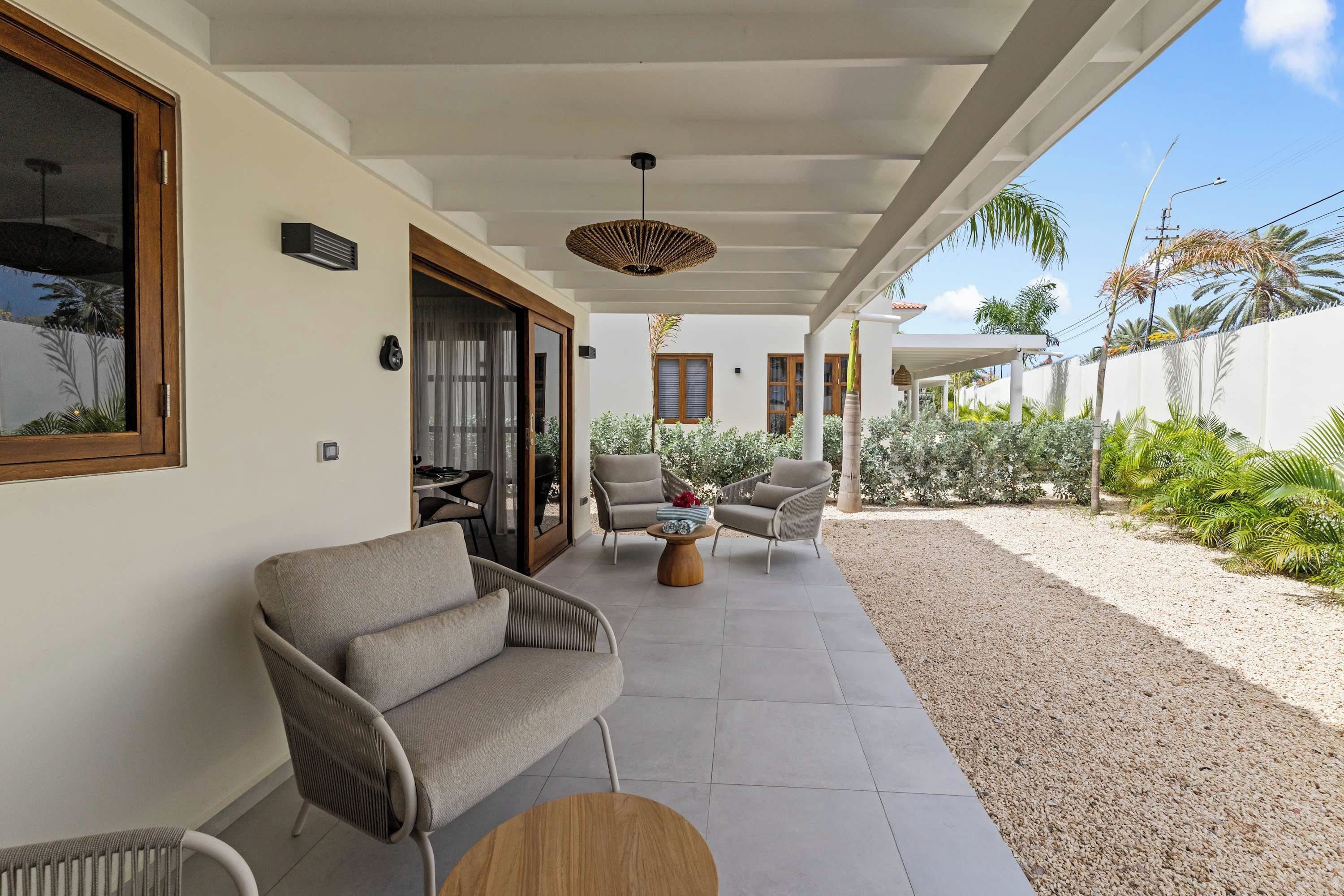 A covered outdoor seating area with a sofa, chairs, and a table.