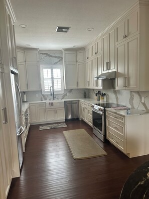 A kitchen with white cabinets, a stainless steel dishwasher, an oven, and a marble backsplash. - Charming 3-bedroom house in Sarasota on a quiet street, 1/2 mile out of town. (Sarasota)