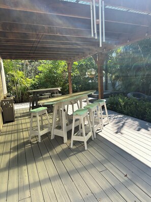 Eine Terrassenanlage aus Holz mit Pergola, Picknicktischen und Bänken.