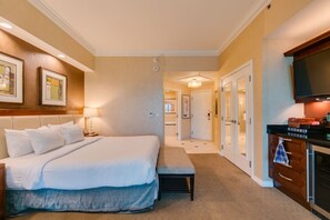 Ein Hotelzimmer mit Bett, Nachttisch, Lampe und Blick auf den Flur zum Badezimmer.