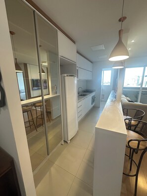 A modern kitchen with a refrigerator, a sink, and a dining area with chairs.