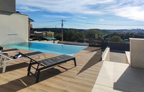 Una piscina sul tetto con lettini e vista sul paesaggio circostante.