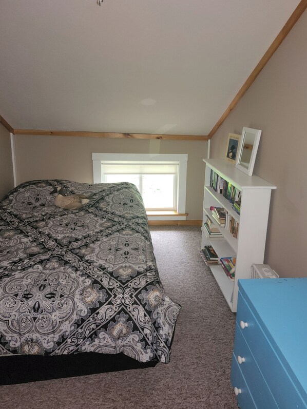 A bedroom with a bed, a window, a bookshelf, and a dresser. - Pet friendly Lakefront Cottage with 4 Bedrooms and plenty of amenities! (Hartland)