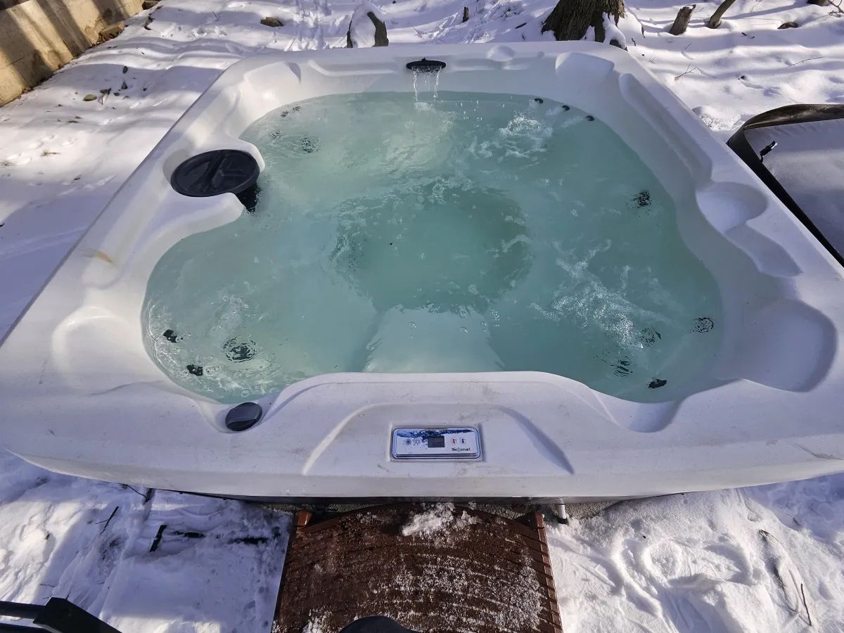 A hot tub partially covered in snow, with water visible inside.