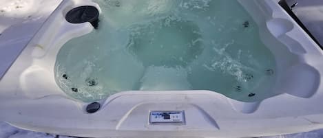 A hot tub partially covered in snow, with water visible inside.