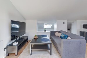 A modern living room with a flat-screen TV, a grey sofa, and a coffee table. - Le Laon - Climatisation - Proche tram (Reims)