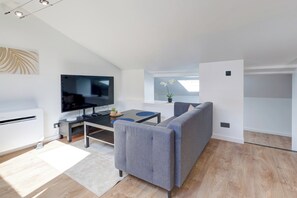 En moderne stue med et fladskærms-tv, en sofa, et sofabord og et spiseområde.