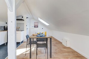 A dining area with a table, chairs, and a view of the kitchen. - Le Laon - Climatisation - Proche tram (Reims)