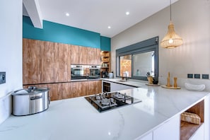 A modern kitchen with a central island, built-in appliances, and a view to the dining area. - Villa Romana - Piscine, jacuzzi - Tampon (Le Tampon)