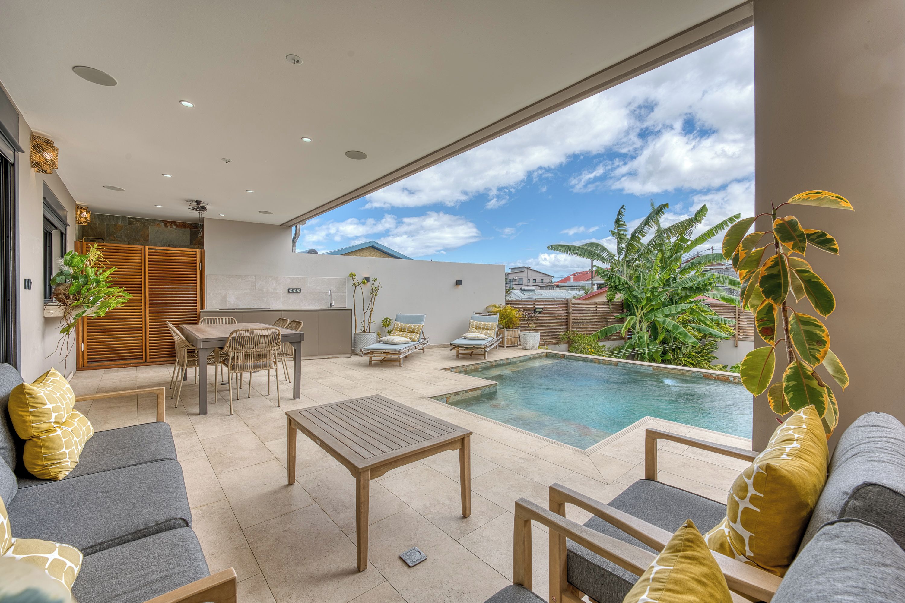 A modern outdoor living space with a pool, seating area, and a view of the sky.