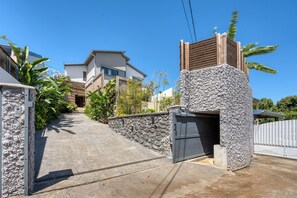 A residential street with houses, a stone wall, and a gated entrance. - Villa Romana - Piscine, jacuzzi - Tampon (Le Tampon)