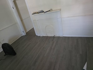 Ein Zimmer mit Holzboden, weißer Wand und einer Tür.