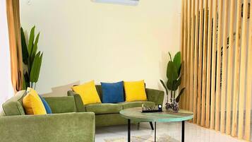 A living room with a sofa, armchairs, a coffee table, and a wooden partition.