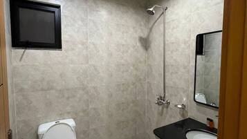 Un bagno moderno con toilette, doccia, lavandino e televisione a muro.