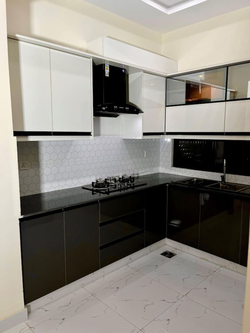 A modern kitchen with black and white cabinetry, a gas stove, and a hexagonal tile backsplash.