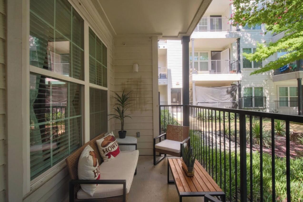 A balcony with a sofa, chairs, and a small table.