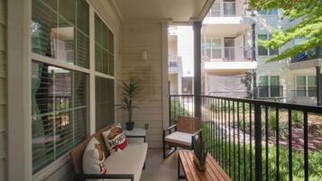 A balcony with a sofa, chairs, and a small table.