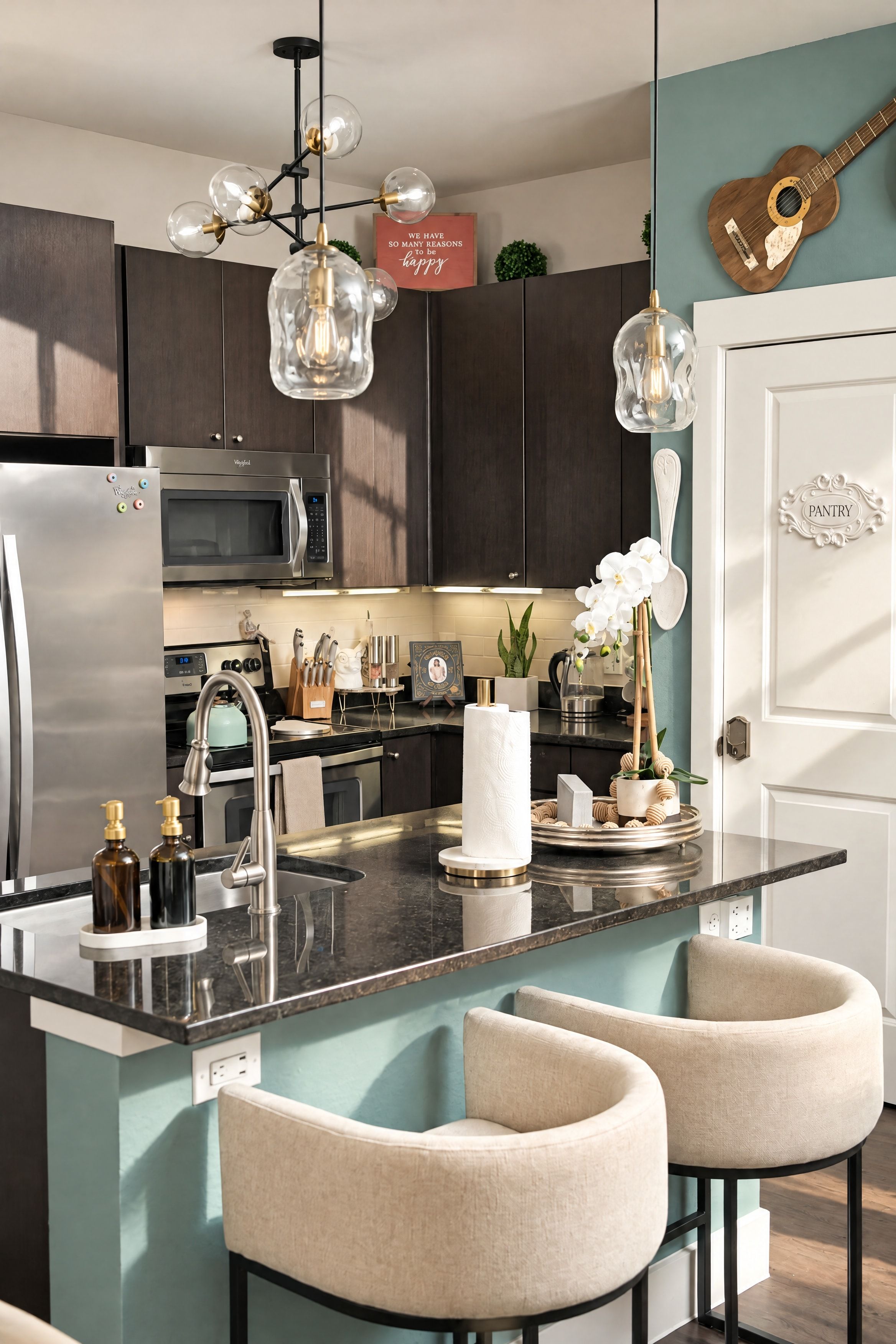 A modern kitchen with a central island, bar stools, stainless steel appliances, and decorative elements.