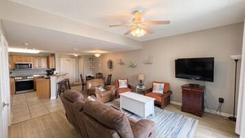 A modern living room with a sofa, a TV, and a ceiling fan.