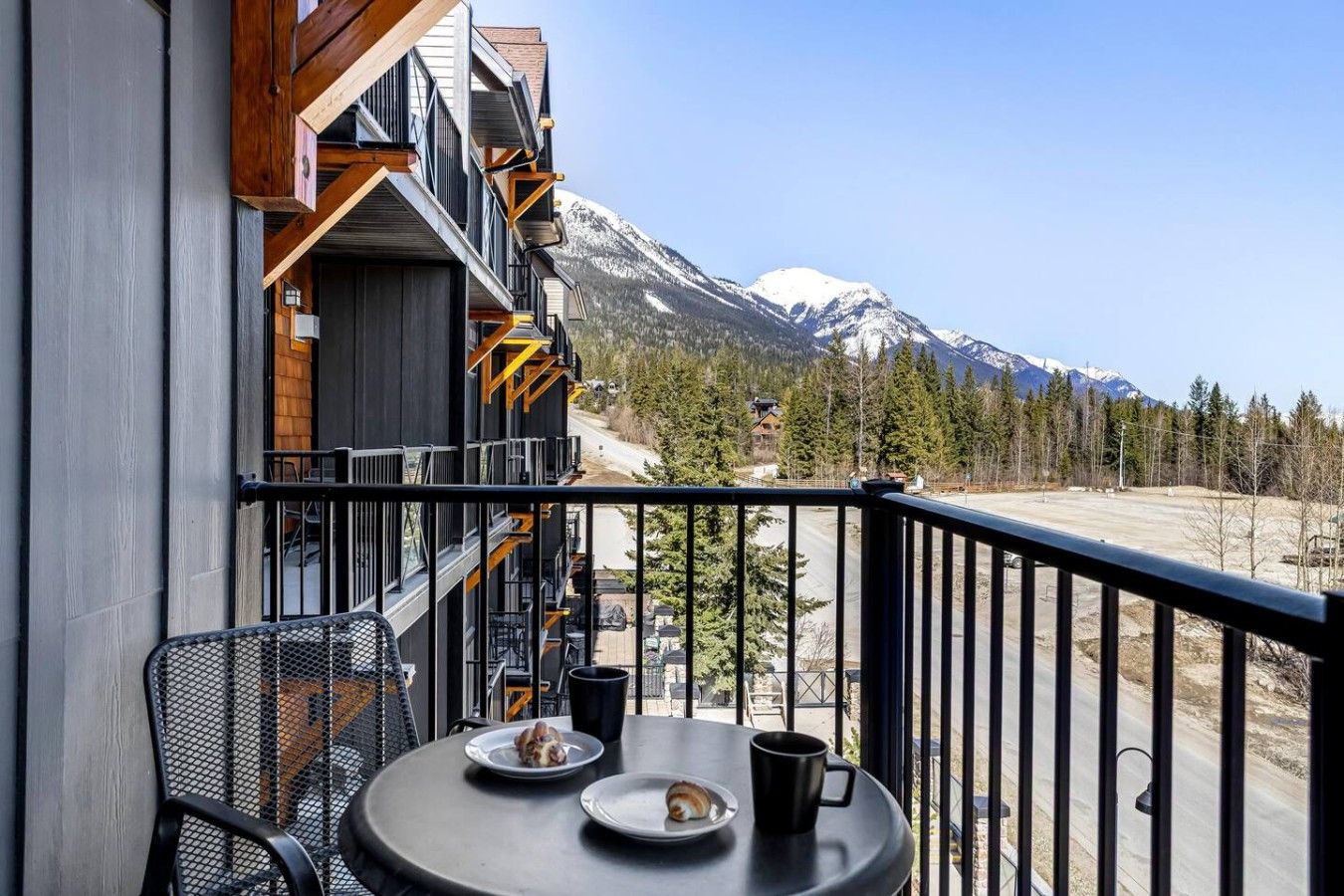 A balcony with a table, chairs, and a mountain view.