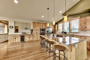 A spacious kitchen with wooden cabinets, a granite countertop, and bar stools. - 4 Bedroom Mountain Contemporary Views! (South Lake Tahoe)