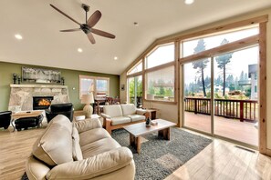 A spacious living room with a fireplace, leather sofas, a coffee table, and large windows offering a view of the outdoors. - 4 Bedroom Mountain Contemporary Views! (South Lake Tahoe)