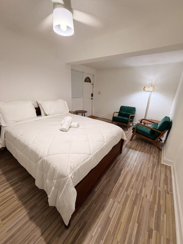 Ein Schlafzimmer mit einem großen Bett, einem Nachttisch, einem Sessel und einer Stehlampe.