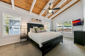 Ein Schlafzimmer mit Bett, Deckenventilator und großen Fenstern.
