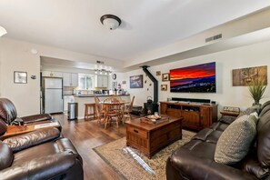 A modern living room with a fireplace, a dining area, and a kitchen in the background. - Upgraded Condo Close to all Tahoe activities! (South Lake Tahoe)