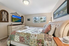Ein Schlafzimmer mit einem Bett, einer Kommode, einem Fernseher und einem Fenster.