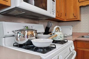A kitchen with a stove, microwave, and various cookware.